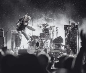 Bilde av BigBang fra en konsert. Øystein Greni er mitt i et hopp med gitaren sin.