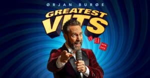 Bildet viser Ørjan Burøe med en mikrofon i hånden foran en tekst som sier "Greatest Vits"